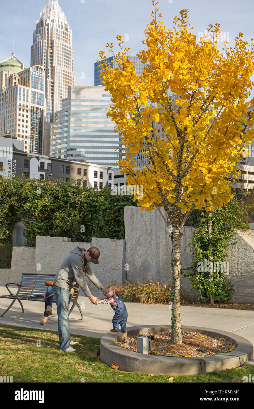 CHARLOTTE, NC - November 25, 2016:  A father plays with his young son in Romare Bearden Park in Uptown Charlotte, North Carolina. Stock Photo