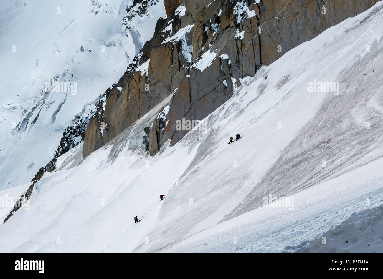 Climbers ascending way up to Aiguille du Midi with details of Aiguille du Plan in background Stock Photo