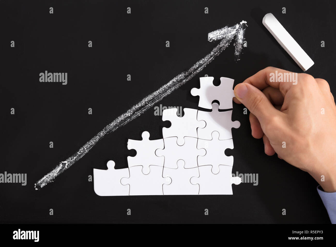 Person Arranging Puzzles On Blackboard Stock Photo