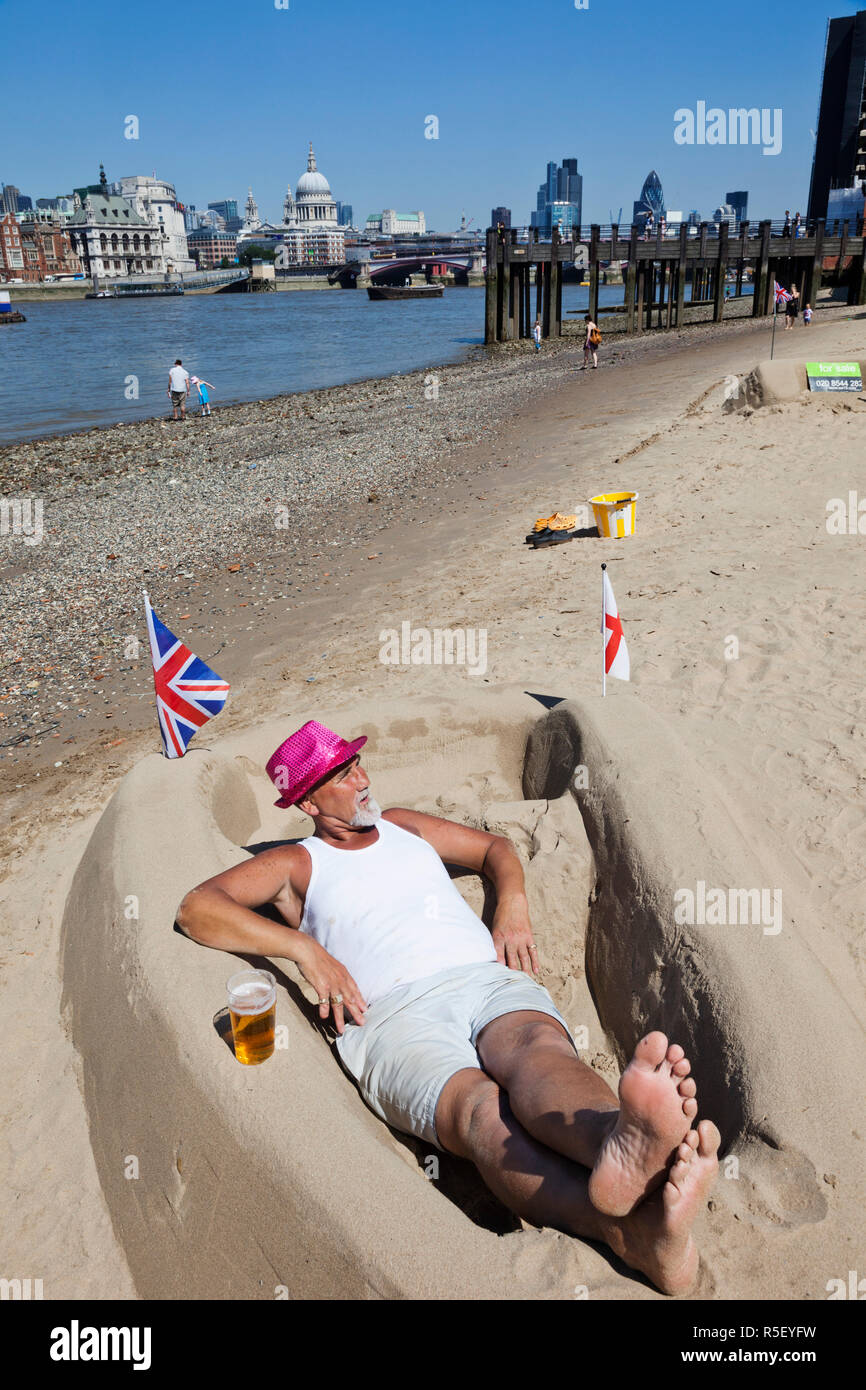 England, London, Bankside, Sand Sculpture Artist Relaxing on Bank of River Thames Stock Photo