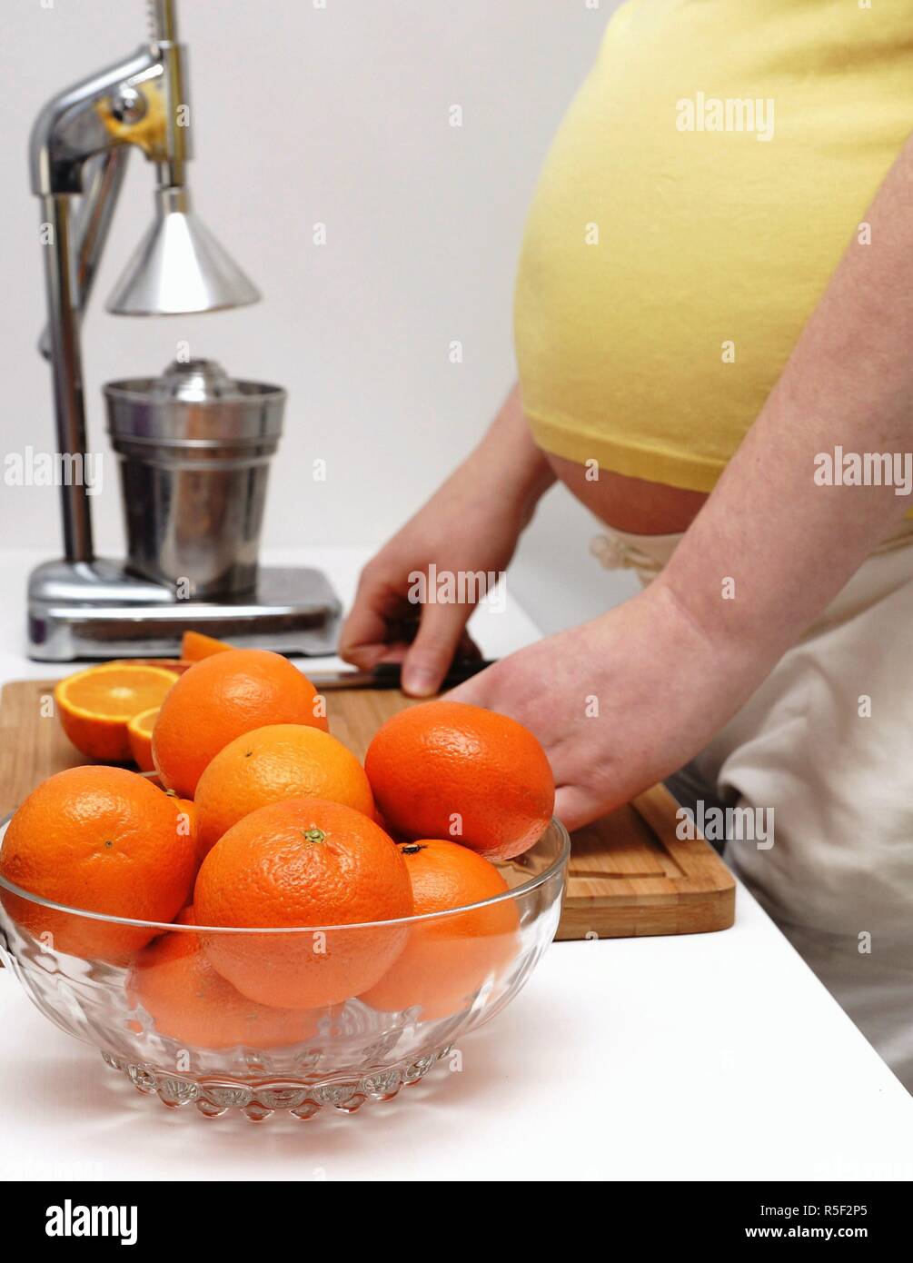 pregnant woman is standing at a table with oranges Stock Photo