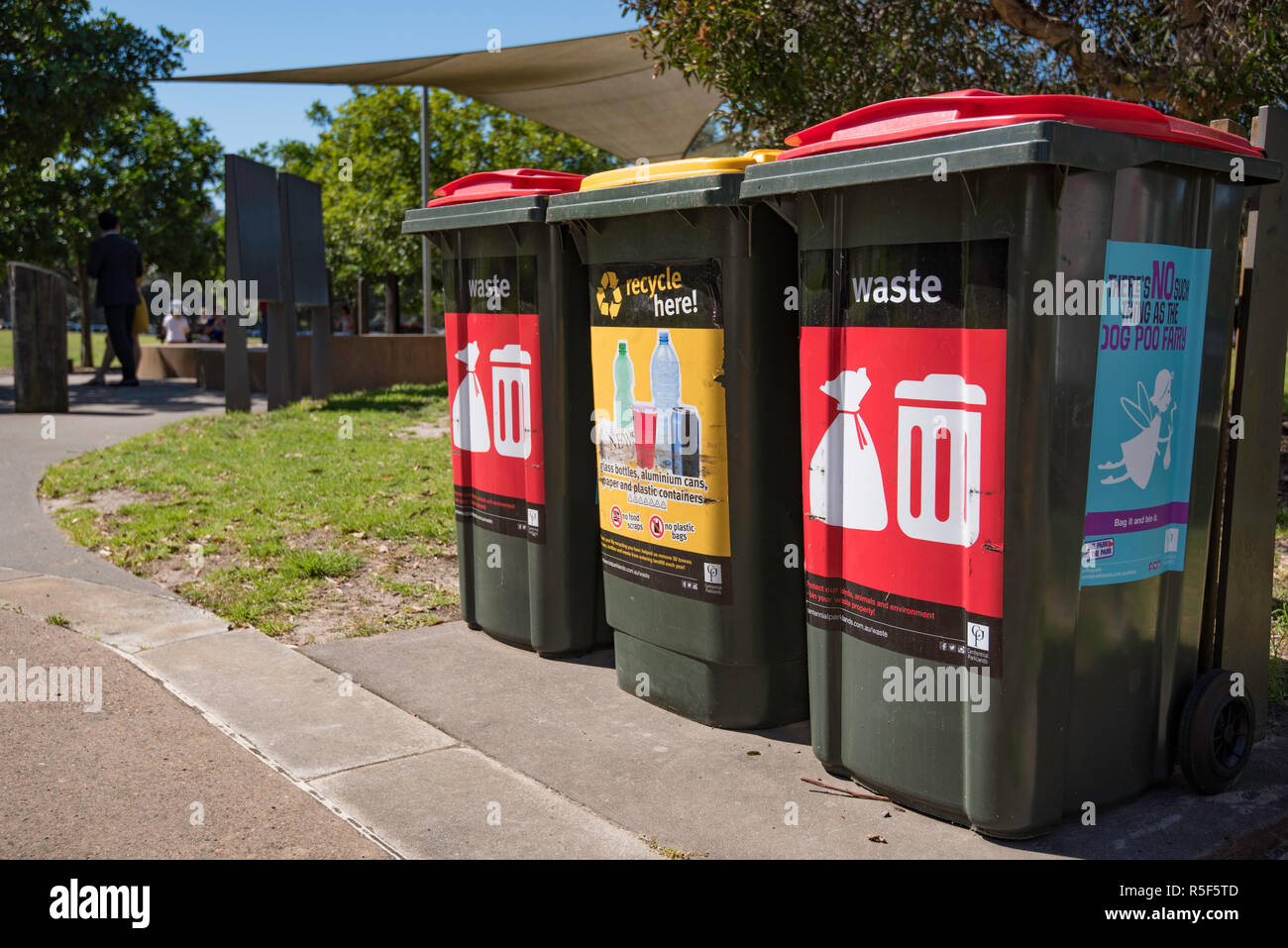 Waste and bottle recycling bins in Centennial Park Sydney, Australia with positive humorous messaging on the side of one bin Stock Photo