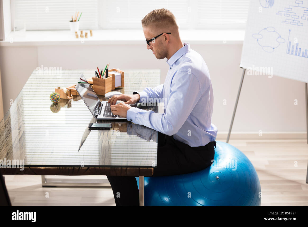 man-sitting-on-exercise-ball-office-hi-res-stock-photography-and