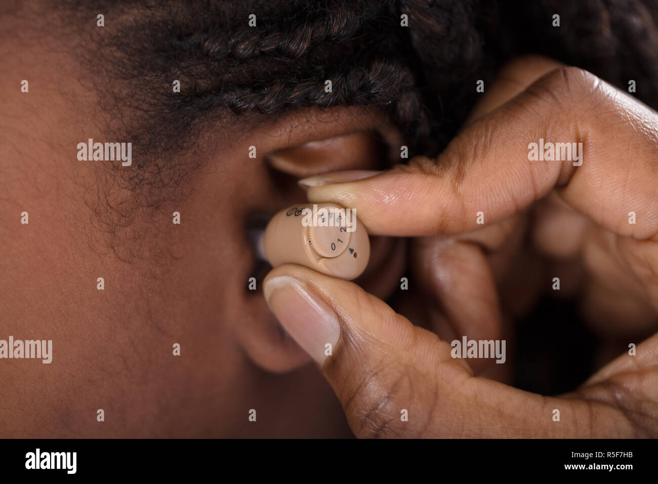 Doctor Inserting Hearing Aid Stock Photo