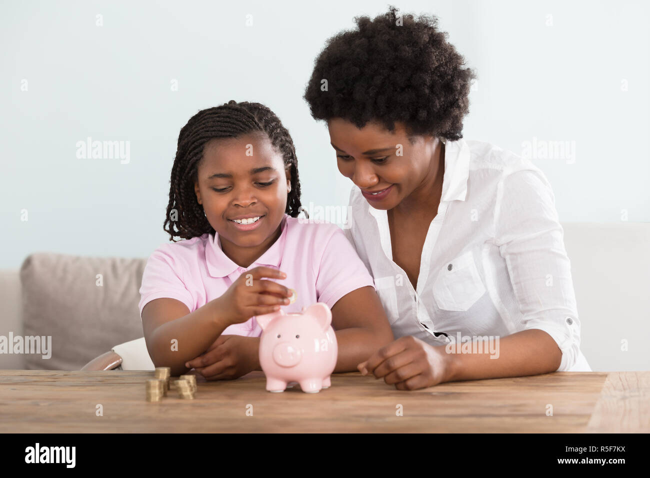 Daughter inserting coin into piggy bank hi-res stock photography and ...