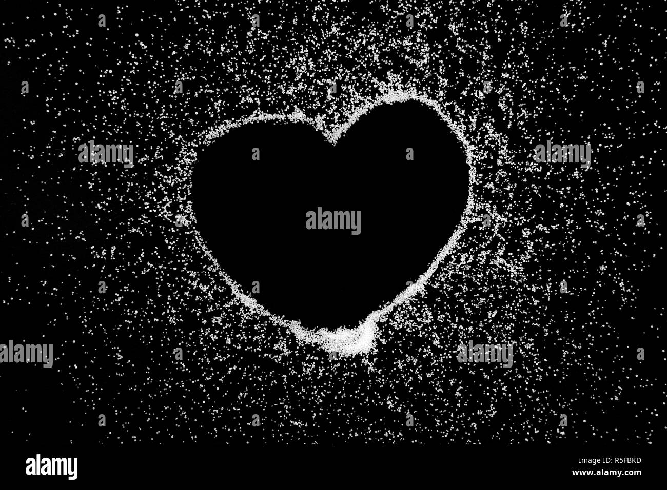 Empty love heart symbol drawing by finger on white salt powder on black background. Romantic St. Valentines Day holidays concept with place for text. Copy space. Stock Photo