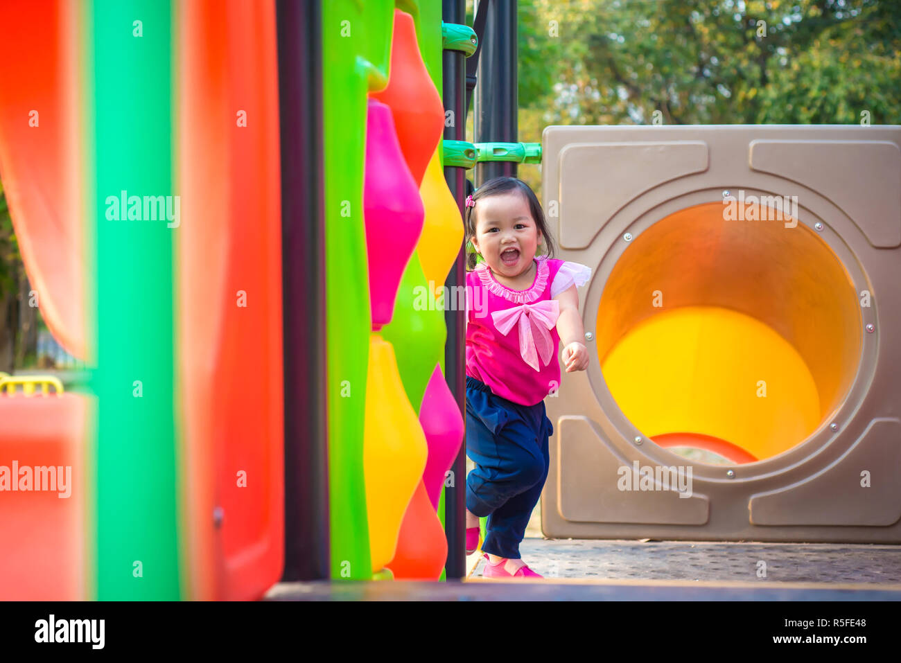 Toddler girl playing on a slide at children playground Stock Photo
