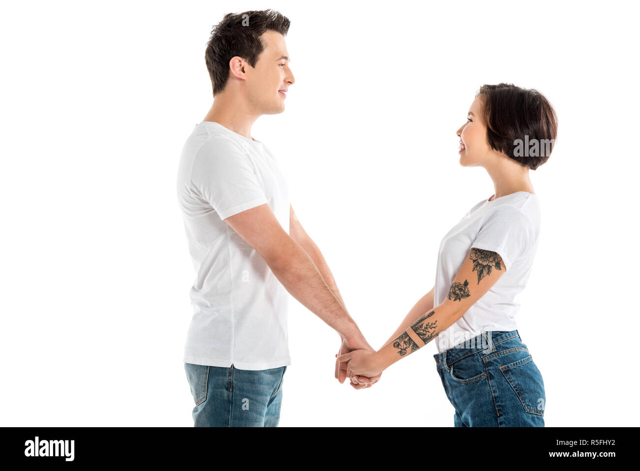 smiling couple holding hands and looking at each other isolated on ...