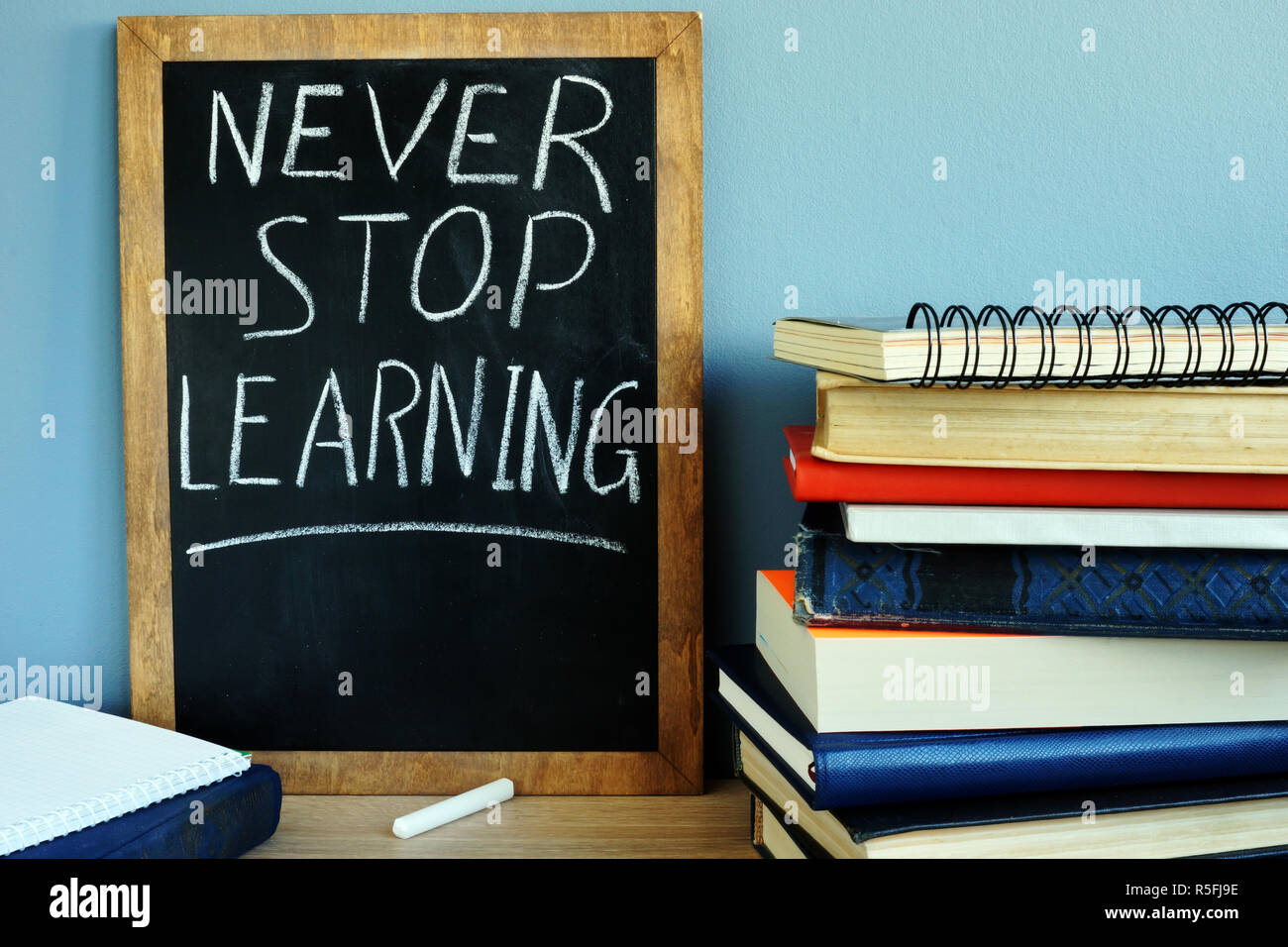 Blackboard with sign Never stop learning and books. Stock Photo