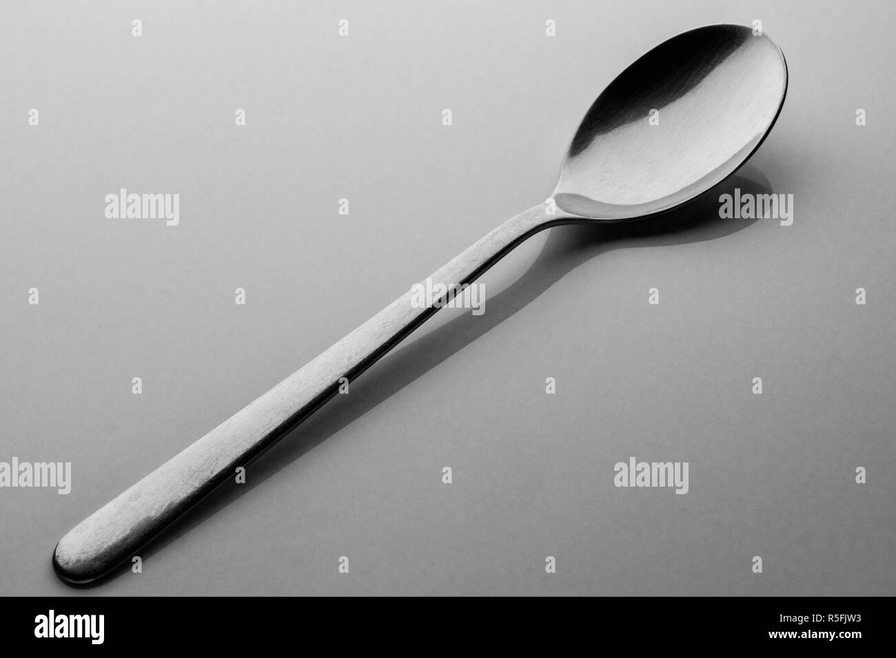 Single silver spoon resting diagonally on a table Stock Photo