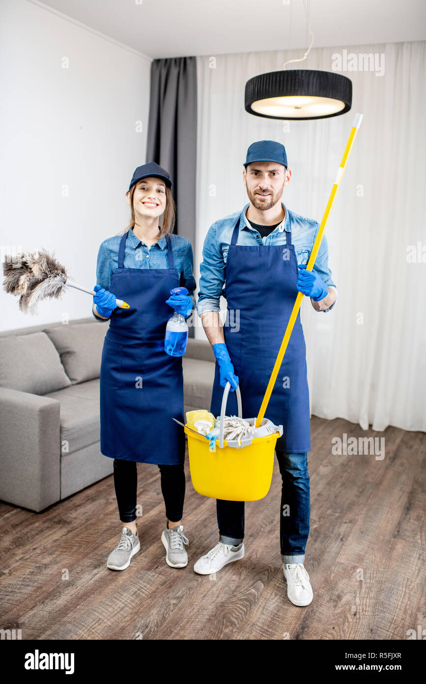 Portrait of a young couple as a professional cleaners in blue uniform