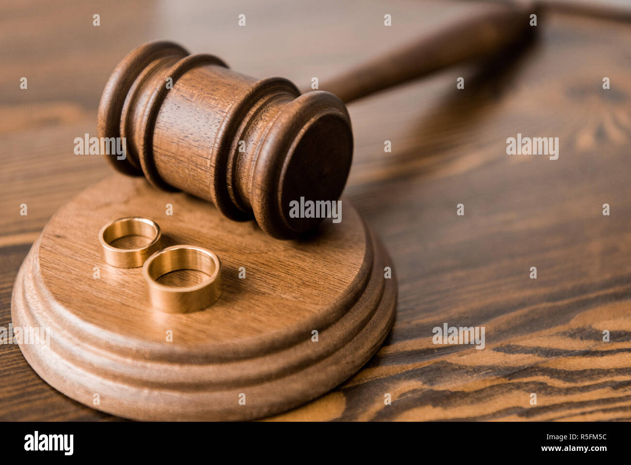 close-up view of wooden hammer and wedding rings on table, divorce concept Stock Photo