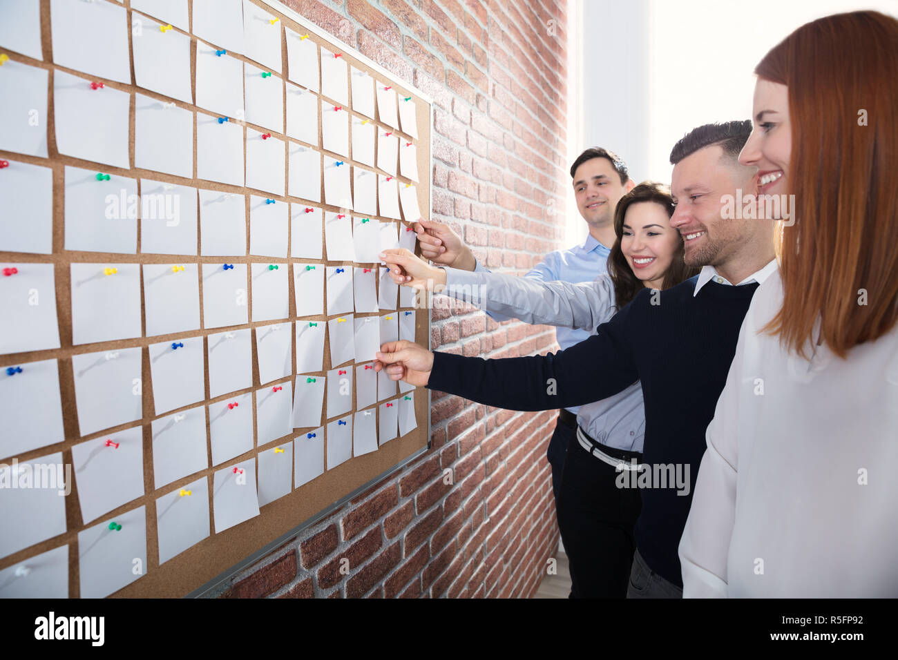 Hands Holding Paper Notes On Corkboard Stock Photo