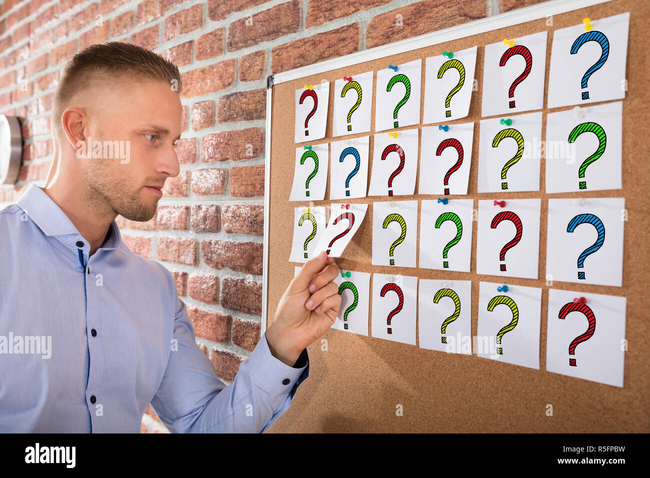 Businessman Looking At Question Marks On Notes Stock Photo