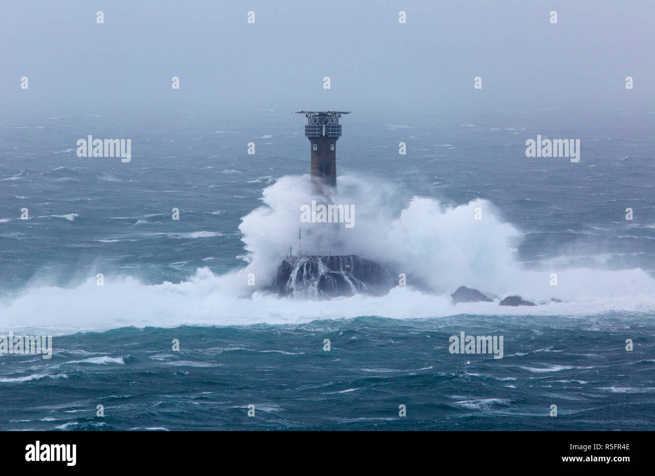 Big waves crashing into the Longships Lighthouse off Lands End Cornwall Stock Photo