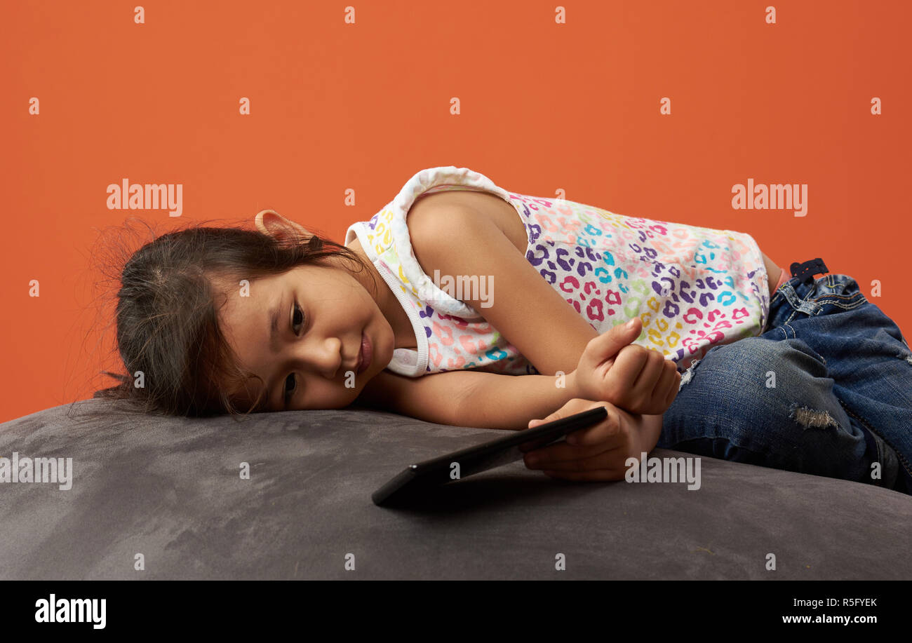 Asian girl sad with phone. 7 years old. Filipina kid. Stock Photo