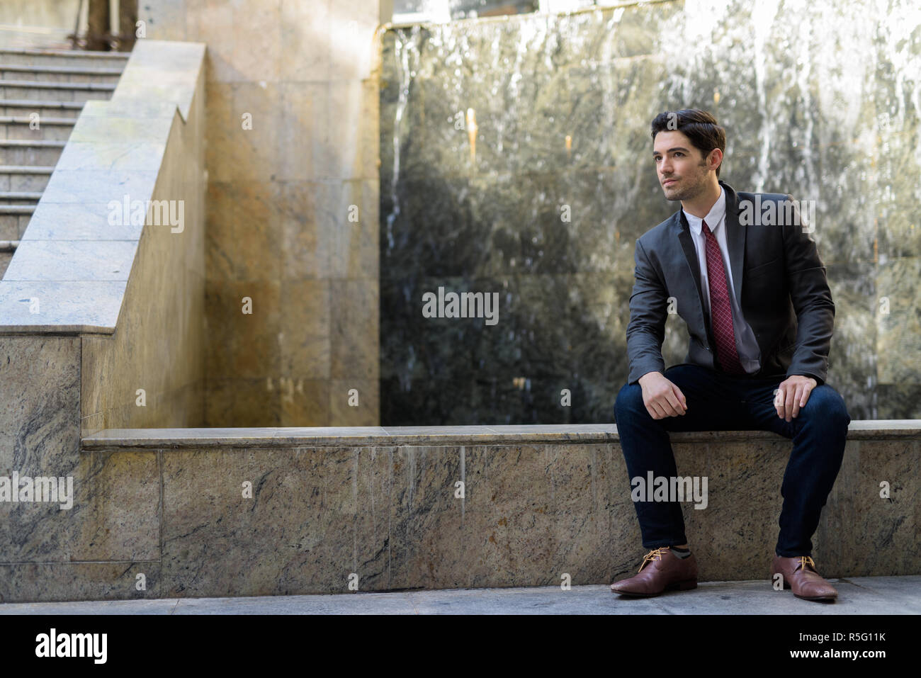 Portrait of young handsome businessman sitting outdoors Stock Photo