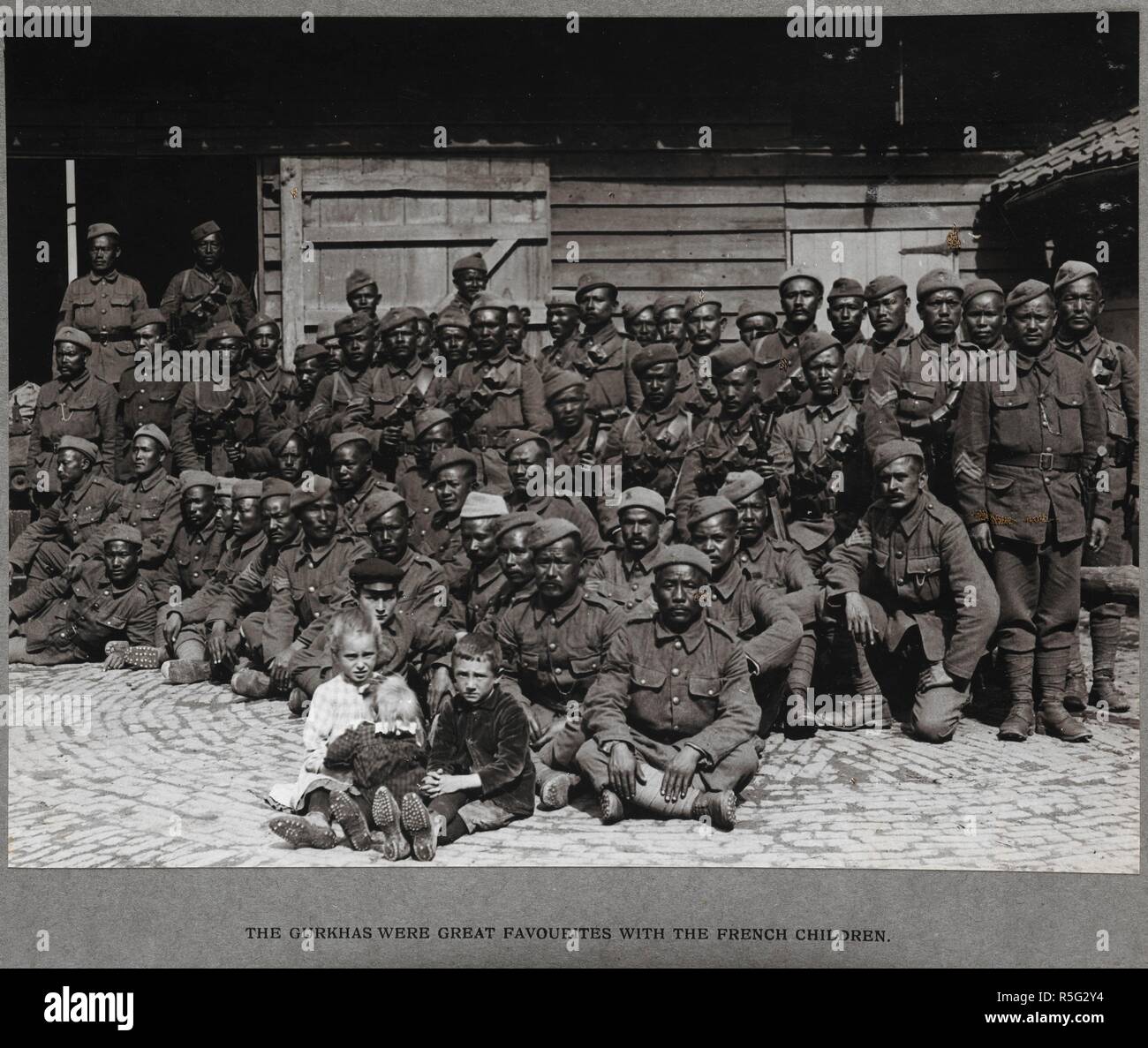 The Gurkhas were great favourites with the French children. Some young children pictured with a large group of Gurkhas. 'India Office Official Record of the Great War'. 22-Apr-21. The photographs appear in a variety of sizes, shapes and colours including shades of blue, green and brown. They record scenes of military life as experienced by the Indian and British armies in France during the First World War. Source: Photo 21/(69). Author: Girdwood, H. D. Stock Photo