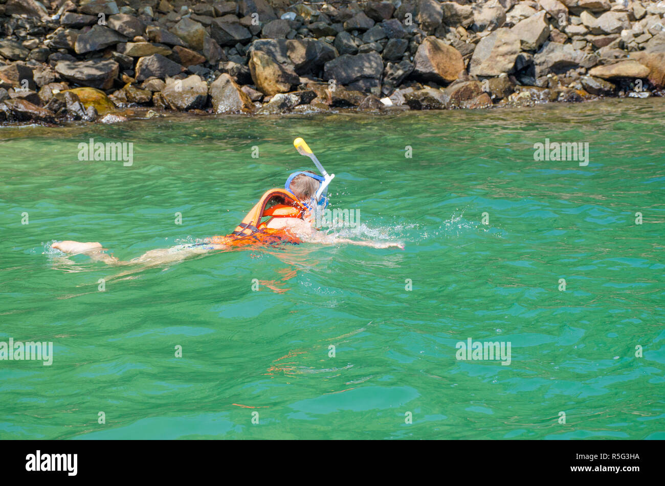 The girl in a mask dives under water to watch the underwater world Stock Photo