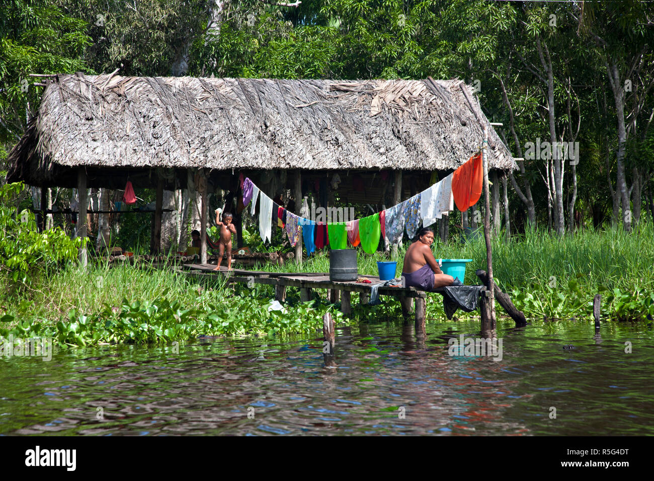 Venezuela, Delta Amacuro, Orinoco Delta, River Manamo, Yavinoco Village, Woman washing clothes on jetty Stock Photo