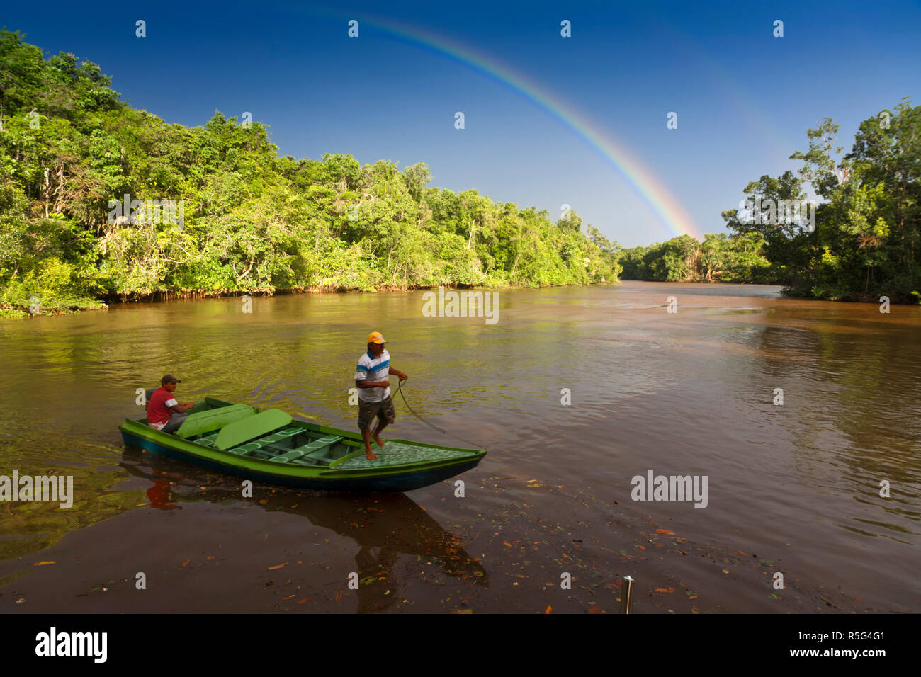 Venezuela, Delta Amacuro, Orinoco Delta, Warao People in boat on Nararina river with rainbow in stormy sky Stock Photo