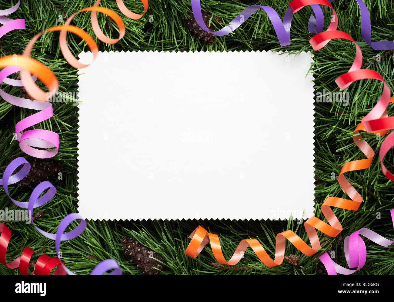 Christmas card on the background of fir branches and festive streamers. Empty white note Stock Photo