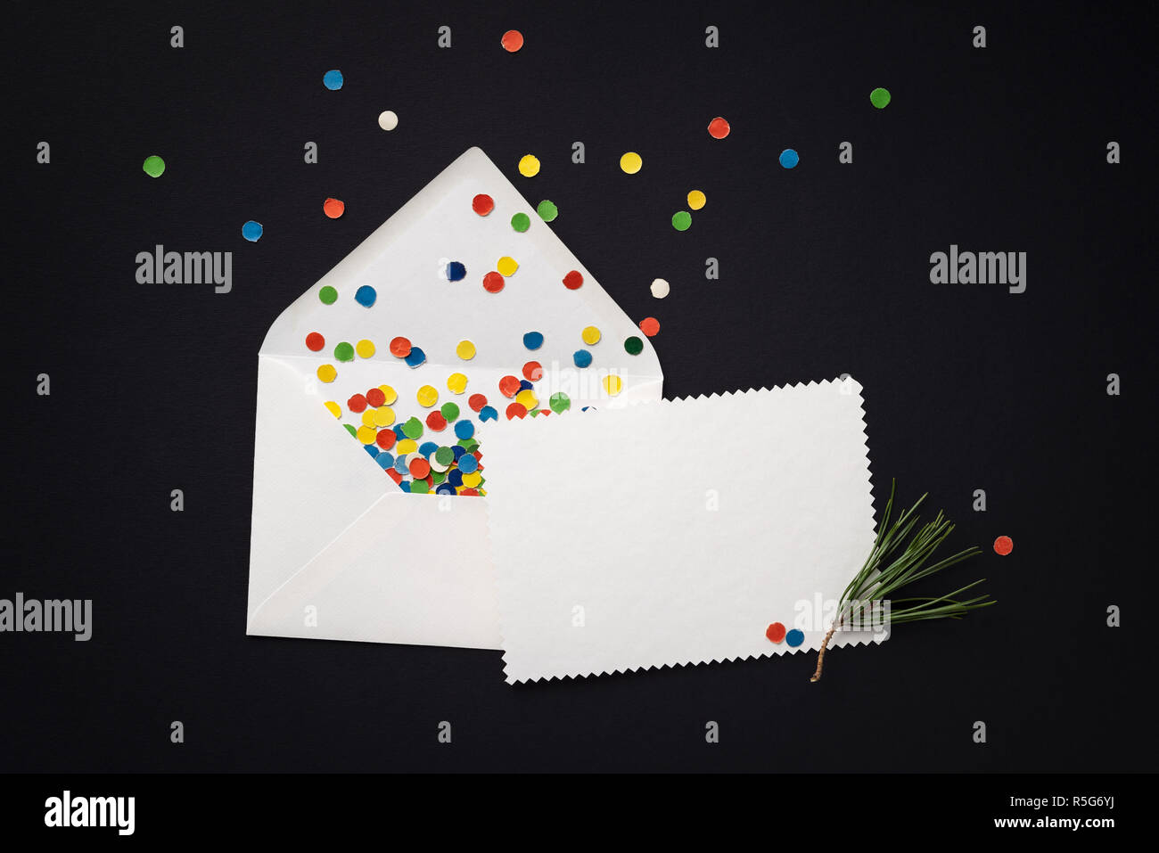 Envelope with Christmas greeting card and festive confetti on a black background. Empty white note Stock Photo