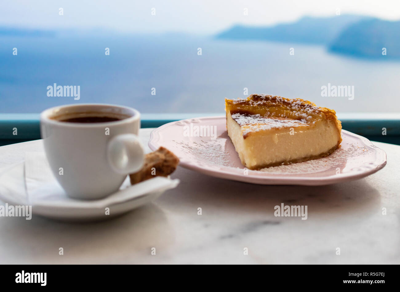 Coffee and cheese cake with sea view in the background, served in a beach cafe in Oia, Santorini, Greece Stock Photo