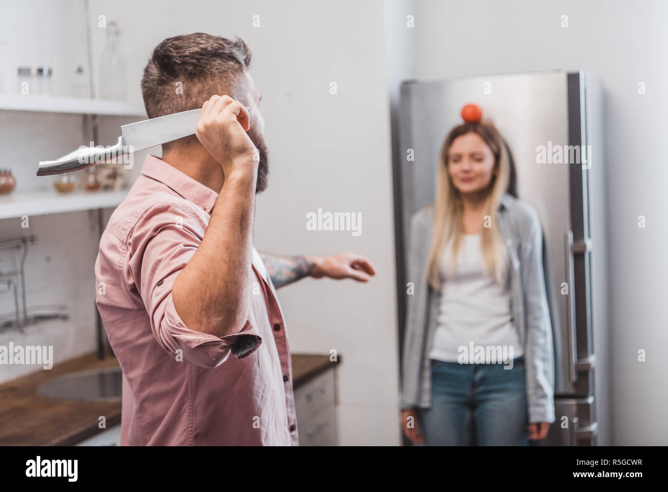 man throwing sharp knife at tomato on woman head while playing dangerous game Stock Photo Alamy