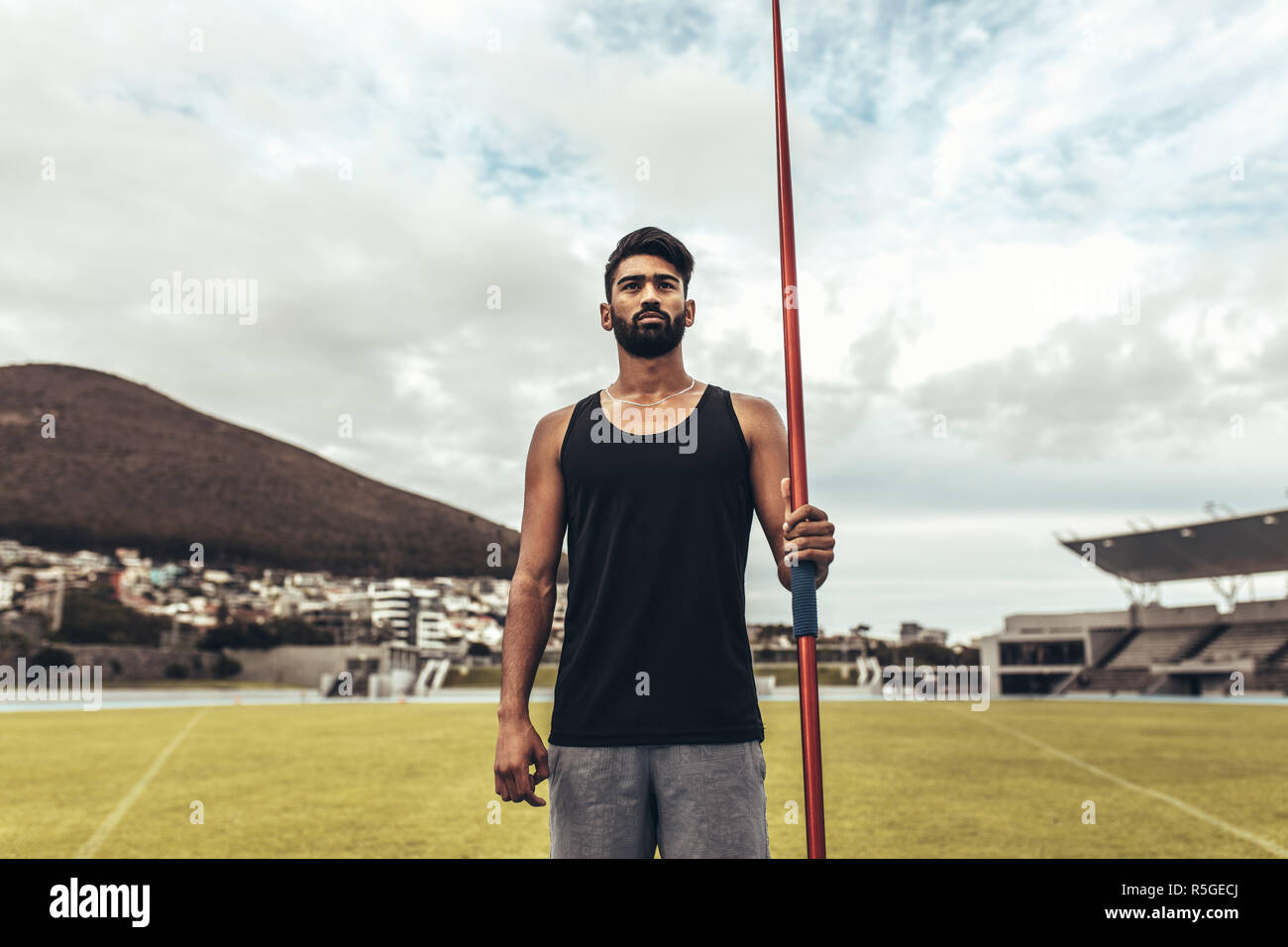 Athlete standing in a track and field stadium holding a javelin. Athlete training in javelin throw standing in a ground. Stock Photo