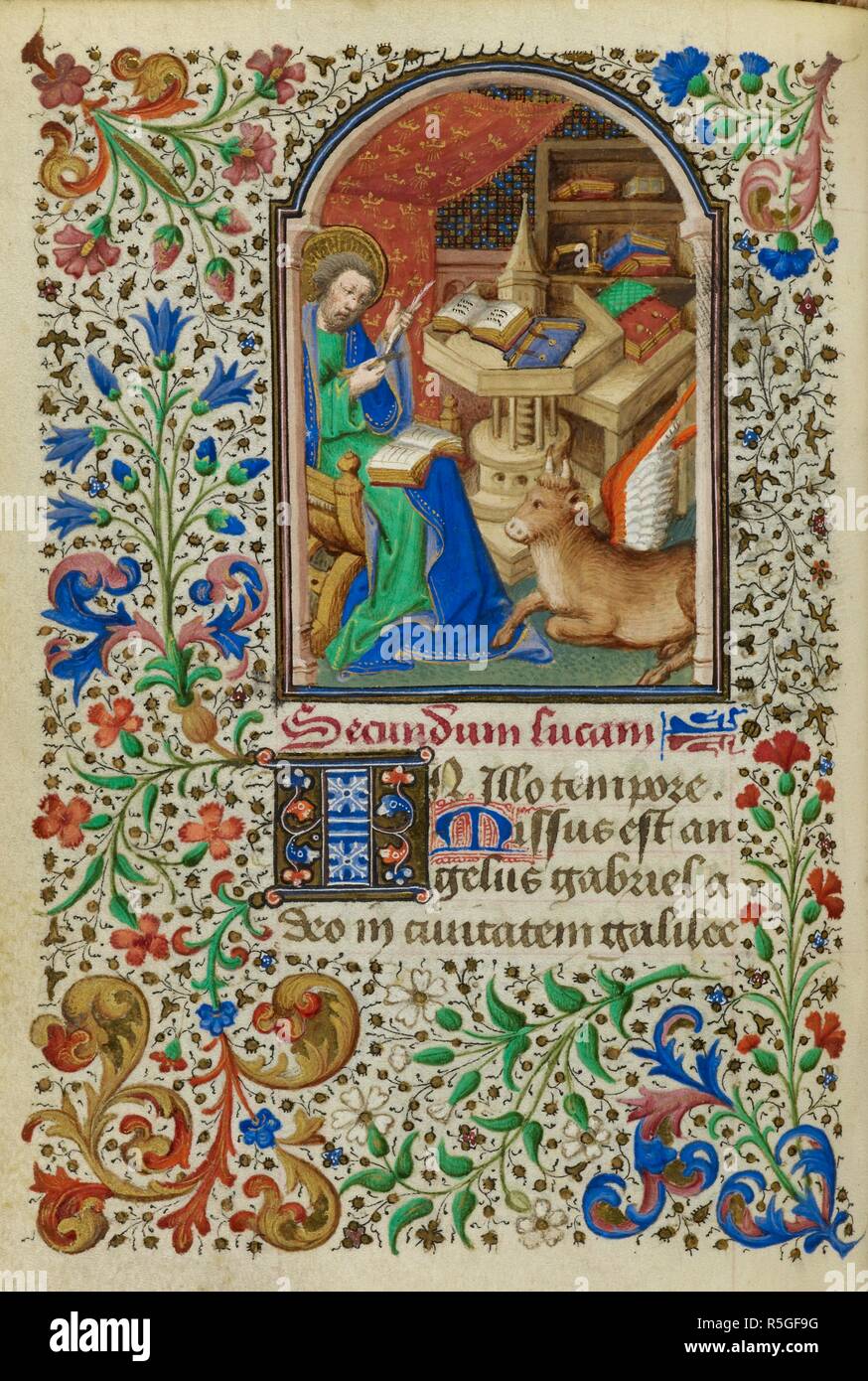 Miniature of Luke seated at a table mending his quill pen with a knife, with his symbol, the winged ox, by his side, and a full foliate border, at the beginning of his Gospel. Book of Hours, Use of Rome ('The Dunois Hours'). France, Central (Paris); c. 1440 - c. 1450 (after 1436). Source: Yates Thompson 3, f.15v. Language: Latin, with a French calendar. Stock Photo