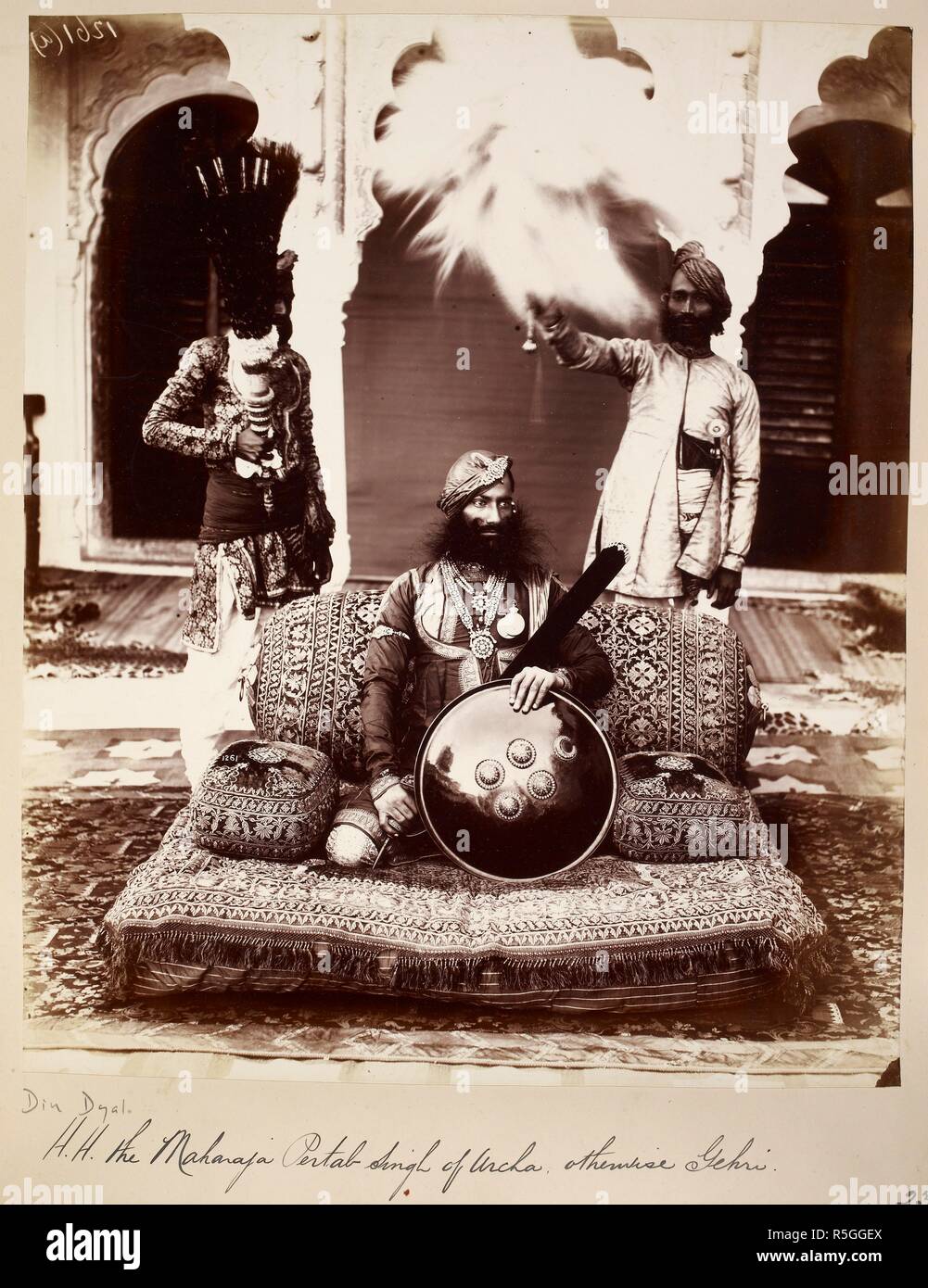 Portrait of H.H. the Maharaja Sir Pratap Singh of Orchha, at Tikamgarh. A full-length portrait, seated on cushions and holding a sword and shield. Two servants, with a fly whisk and fan, stand behind the Maharaja. Archaeological Survey of India Collections: India Office Series (volume 16: Central India and Gujarat). c. 1882. Photograph. Source: Photo 1000/16(1658). Language: English. Author: Dayal, Deen. Stock Photo