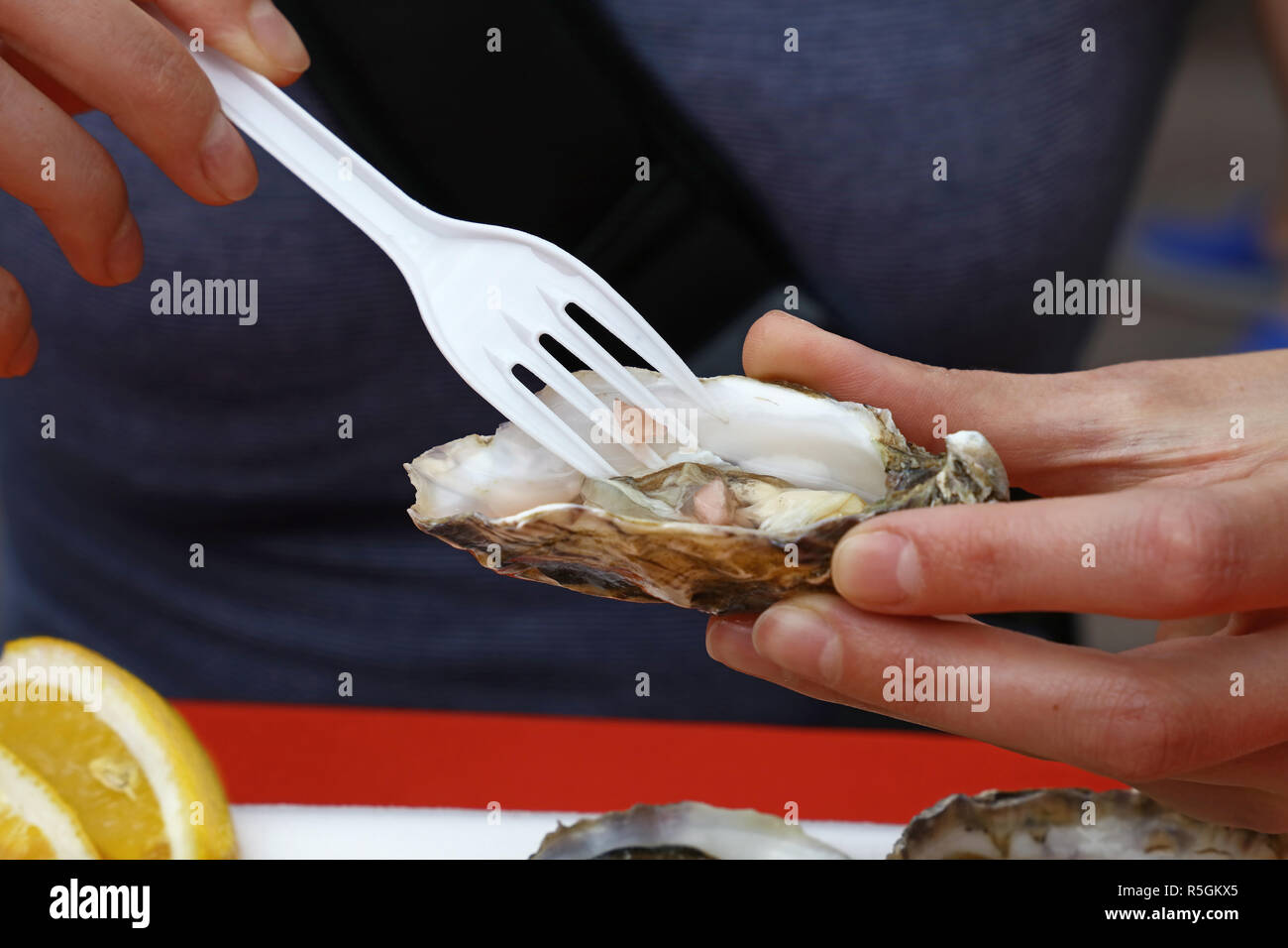 Woman eating oyster with plastic fork Stock Photo Alamy
