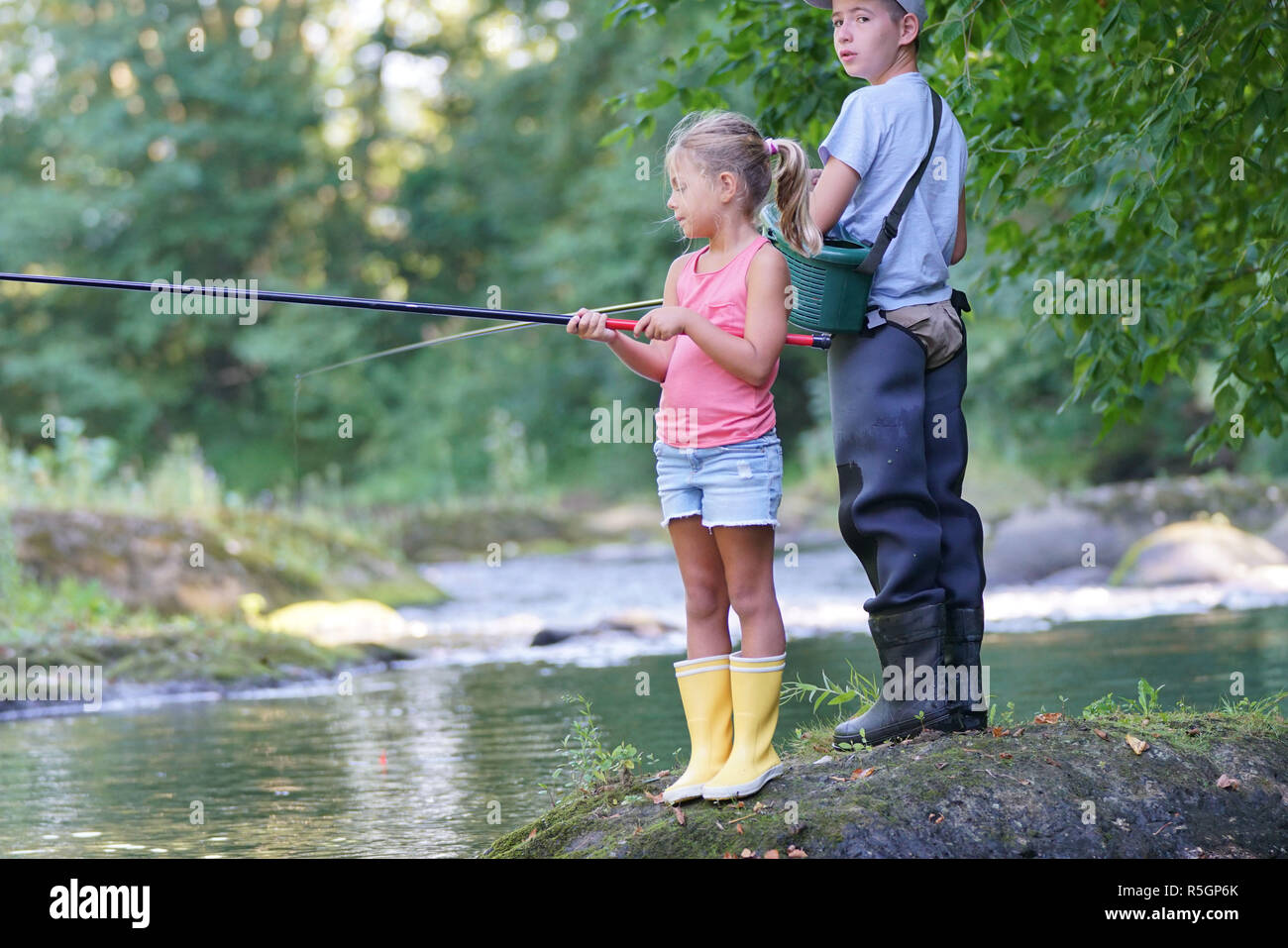 Happy kids fishing in river Stock Photo - Alamy