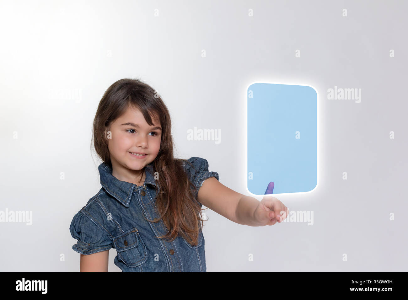 Smiling little girl is touching transparent rectangle by her index ...
