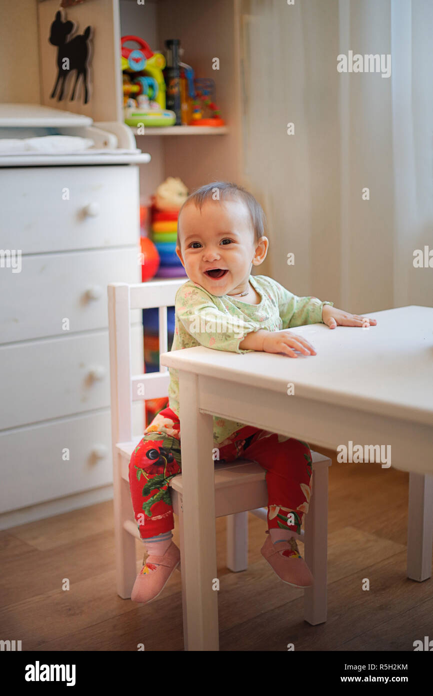 Small child sitting at a white table in kindergarten Stock Photo Alamy