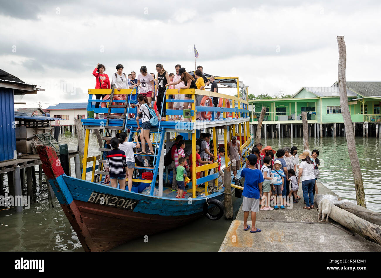 Pulau Ketam, Malaysia December 30, 2017: Unidentified tourists alighting from touring wooden boat at jetty in Pulau Ketam, Malaysia - wooden colorful  Stock Photo