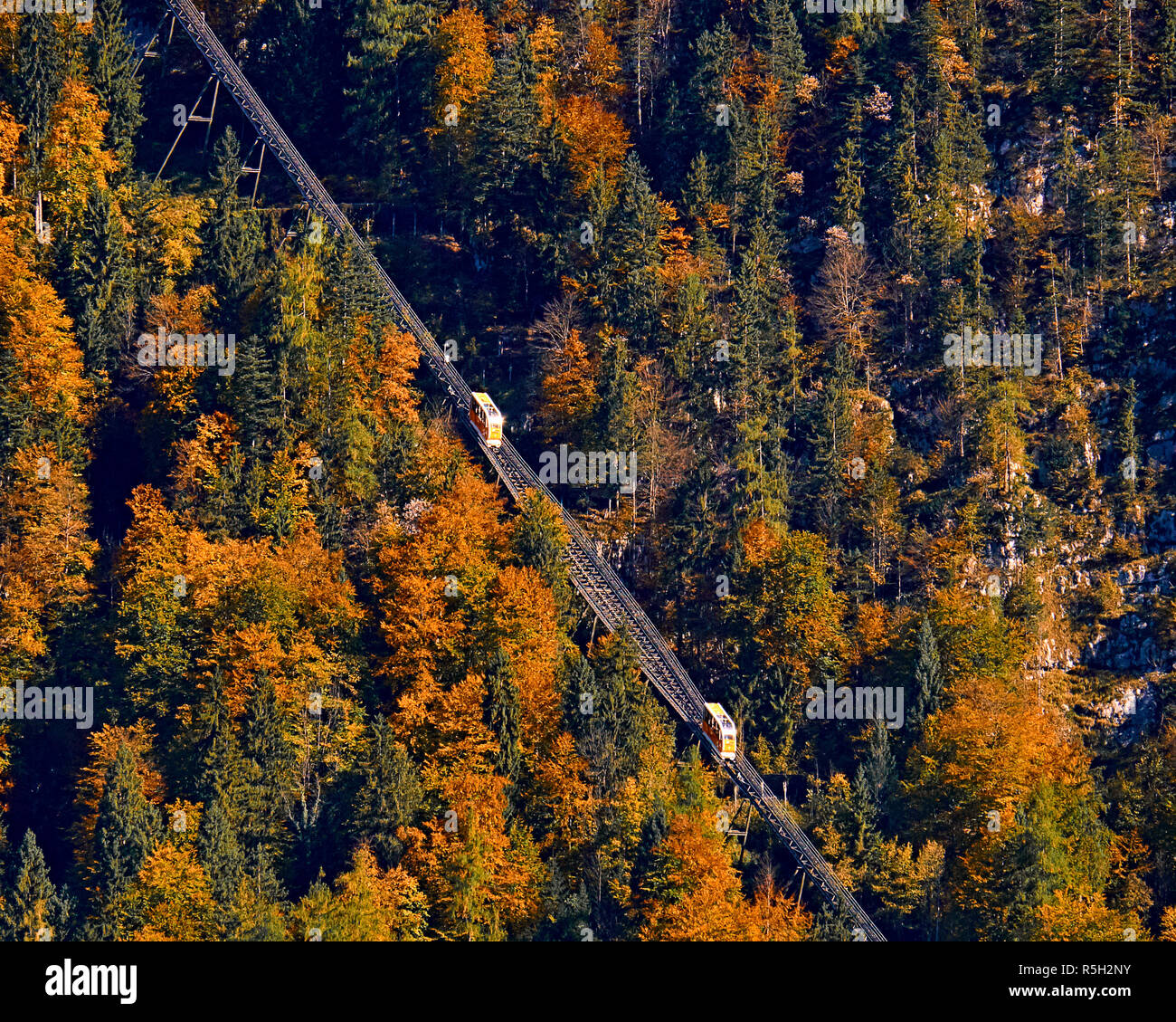 Beautiful aerial fall view of cable car ropeway funicular in austrian alps. Red cable railway car in the mountains by resort village Hallstatt, Salzka Stock Photo