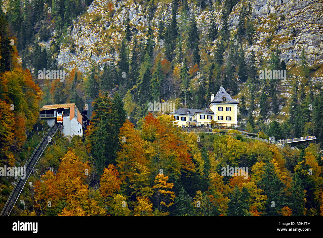 Beautiful aerial fall view of cable car ropeway funicular in austrian alps. Red cable railway car in the mountains by resort village Hallstatt, Salzka Stock Photo