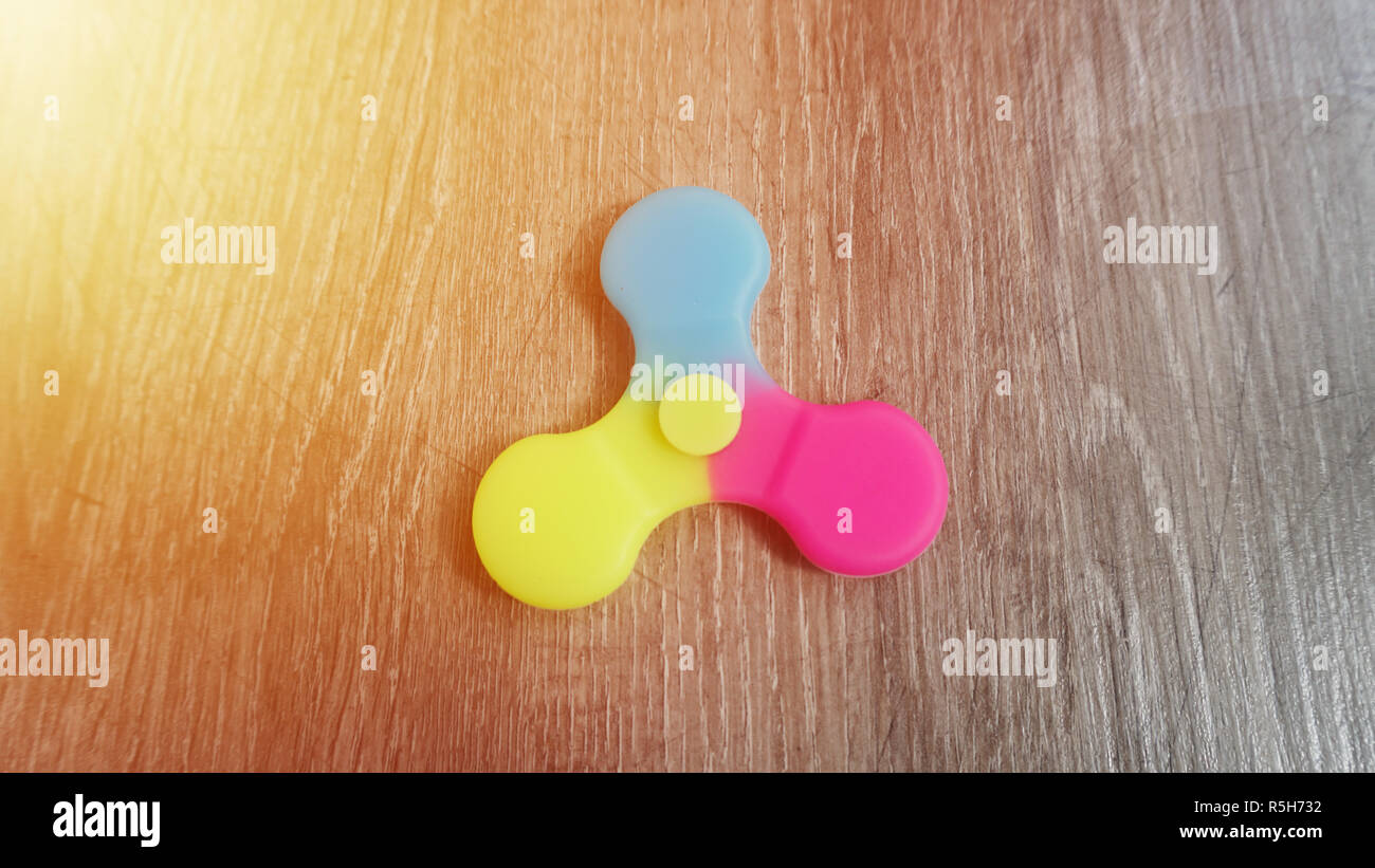 Playing with the colorful Fidget Spinner. Toy spinner in hand.Sun effect Stock Photo