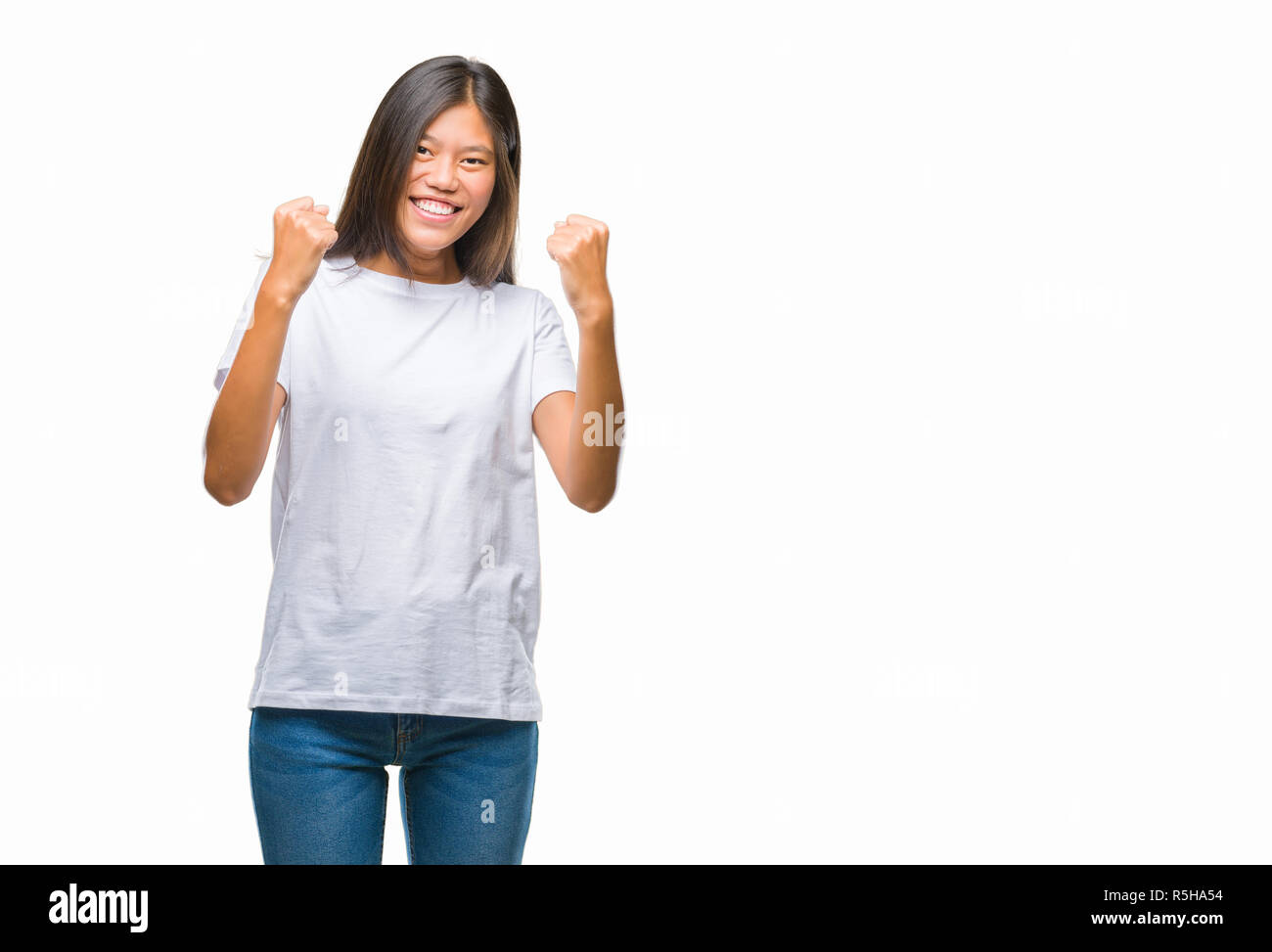 Young asian woman over isolated background very happy and excited doing winner gesture with arms raised, smiling and screaming for success. Celebratio Stock Photo