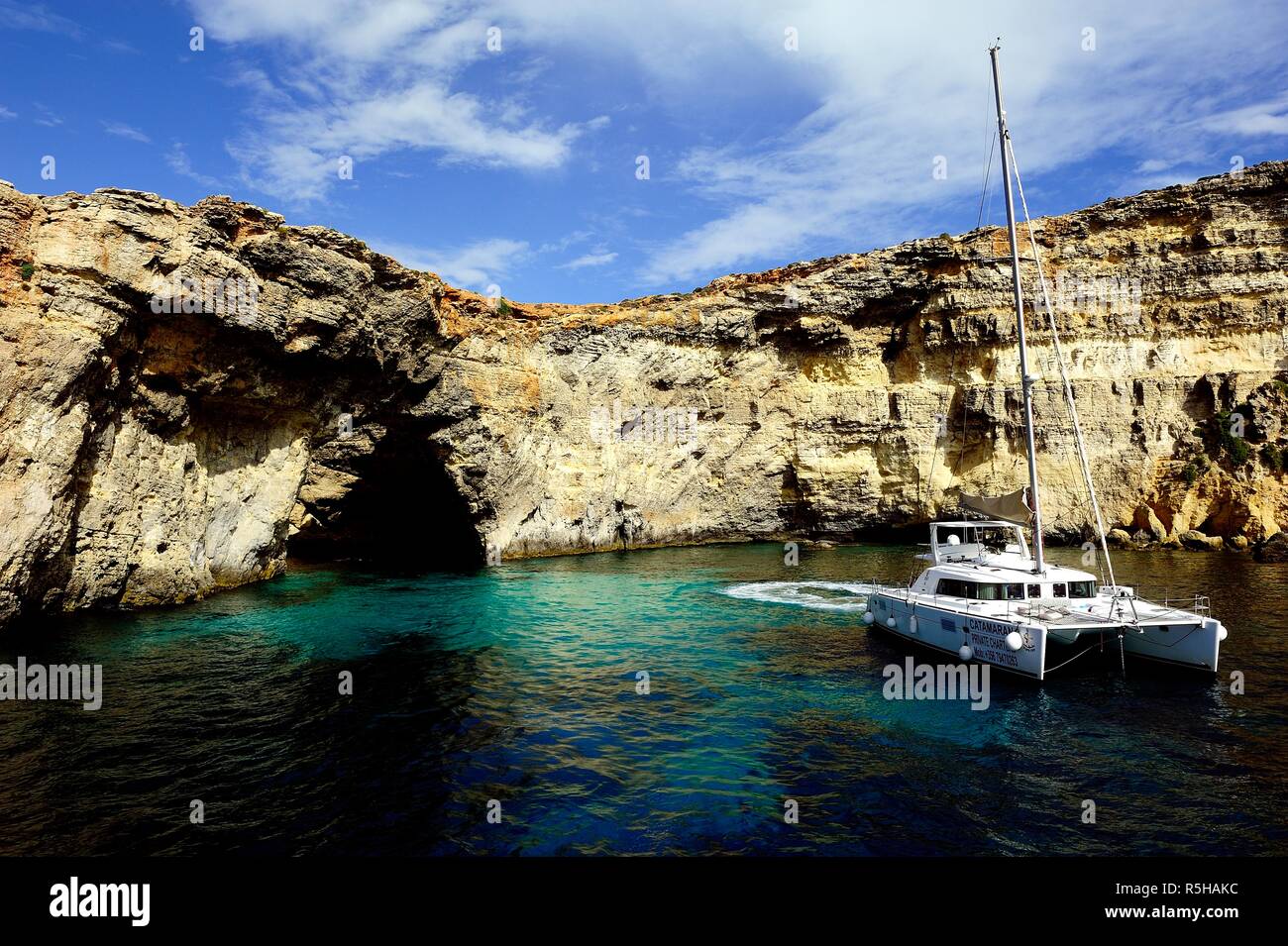 Comino, Malta - 12th October 2018:Catamaran at anchor below the cliffs of Comino Stock Photo