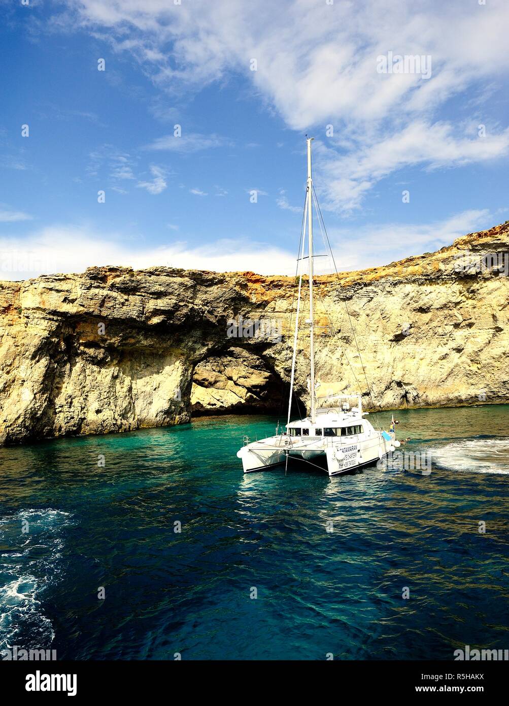 Comino, Malta - 12th October 2018:Catamaran at anchor below the cliffs of Comino Stock Photo