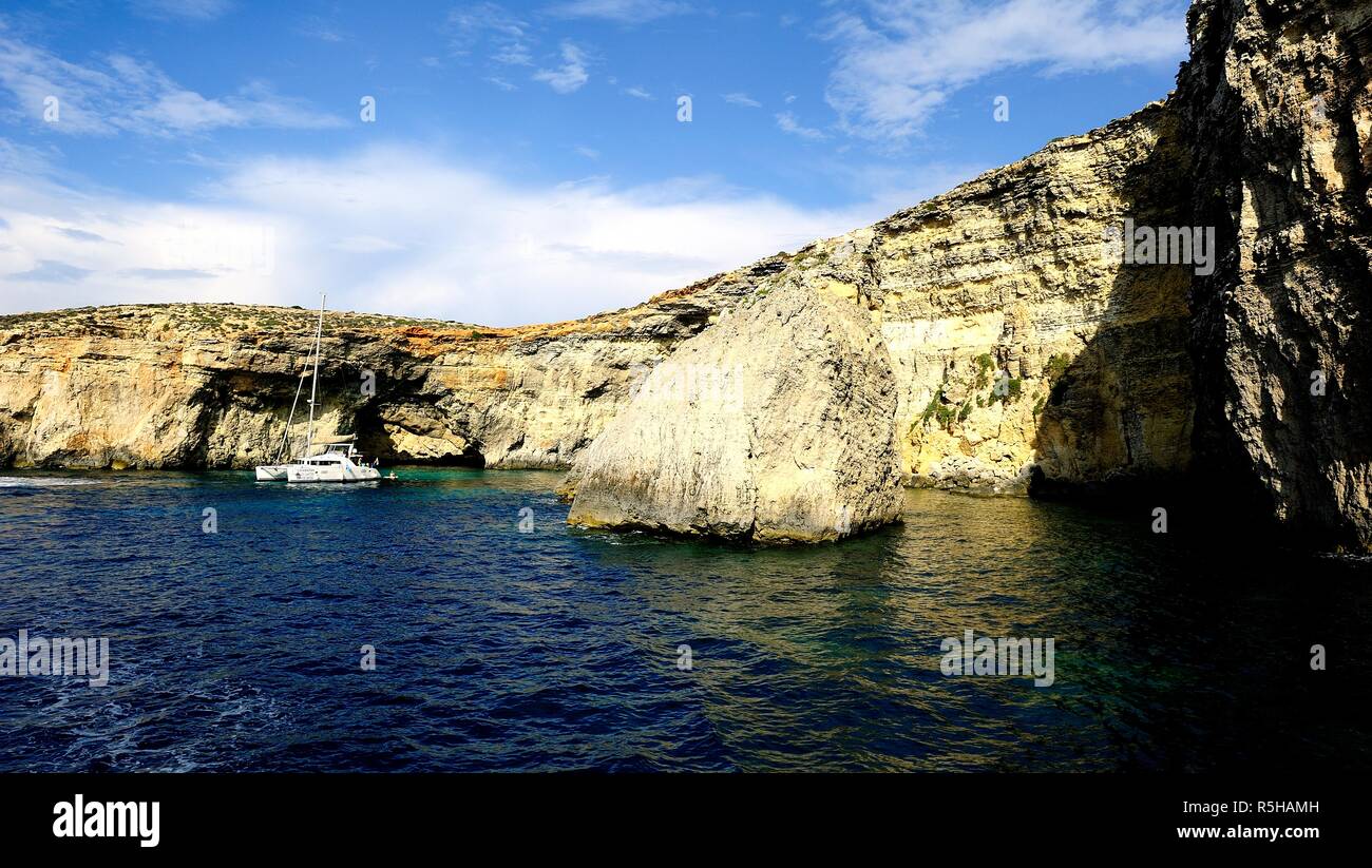 Comino, Malta - 12th October 2018:Catamaran at anchor below the cliffs of Comino Stock Photo