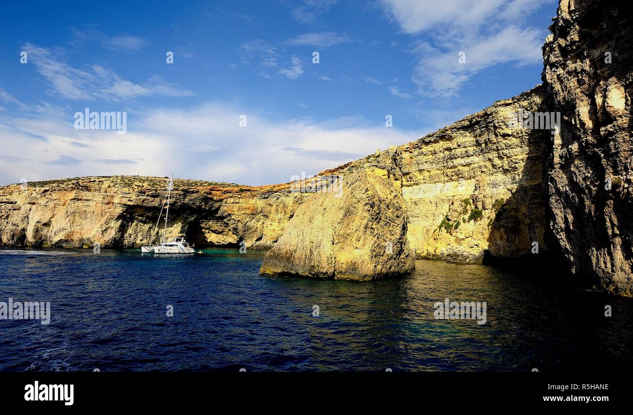 Comino, Malta - 12th October 2018:Catamaran at anchor below the cliffs of Comino Stock Photo