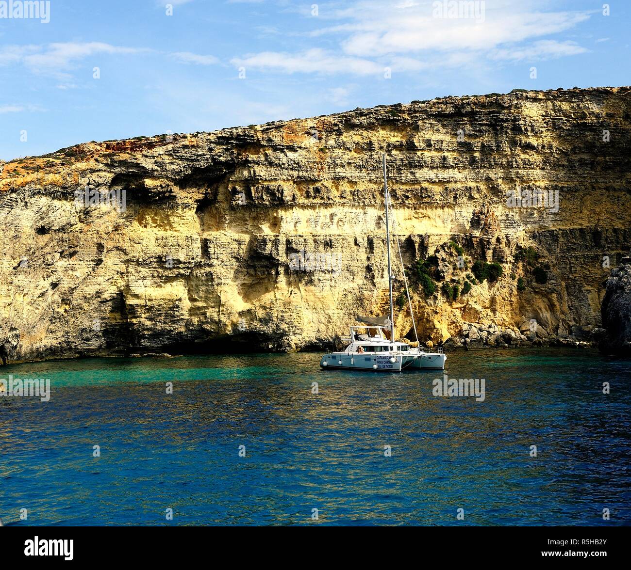 Comino, Malta - 12th October 2018:Catamaran at anchor below the cliffs of Comino Stock Photo