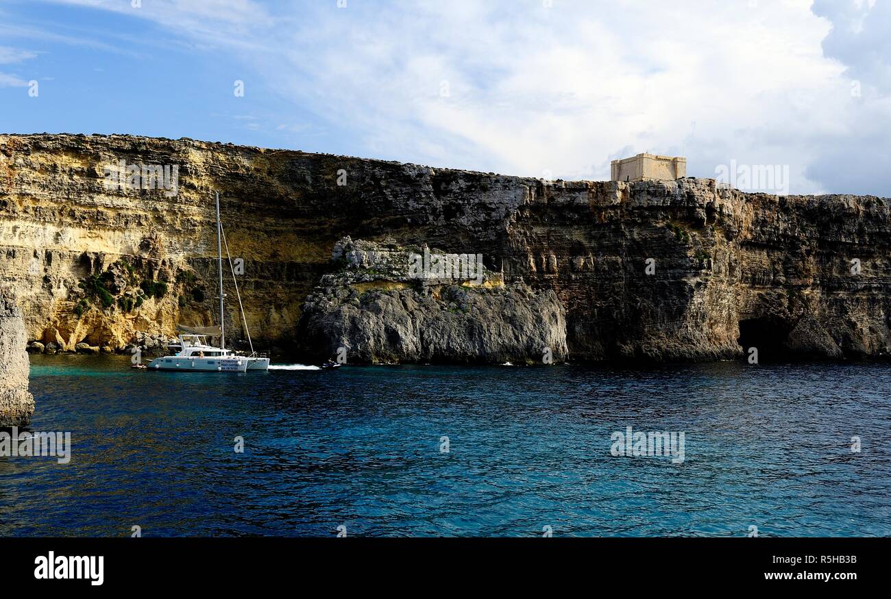 Comino, Malta - 12th October 2018:Catamaran at anchor below the cliffs of Comino Stock Photo