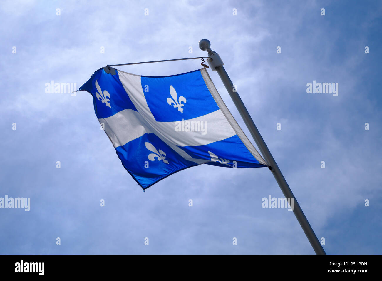 national Quebec flag in Canada fluttering in the wind on blue sky Stock Photo