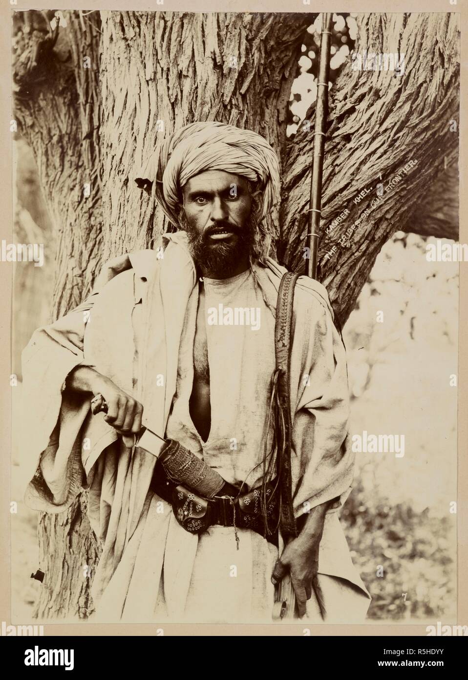 Kamber Khel. The tribes on our frontier. A half-length portrait of a Kambar Khel man, posed in the act of drawing a knife from a sheath at his waist. The Kambar Khels are a sub-division of the Afridis, numbering some 4,500 fighting men at the turn of the century . Photograph Album of Josephine Eppes: Views of India and Hong Kong. 1890s. Photograph. Source: Photo 867/2(1). Author: UNKNOWN. Stock Photo