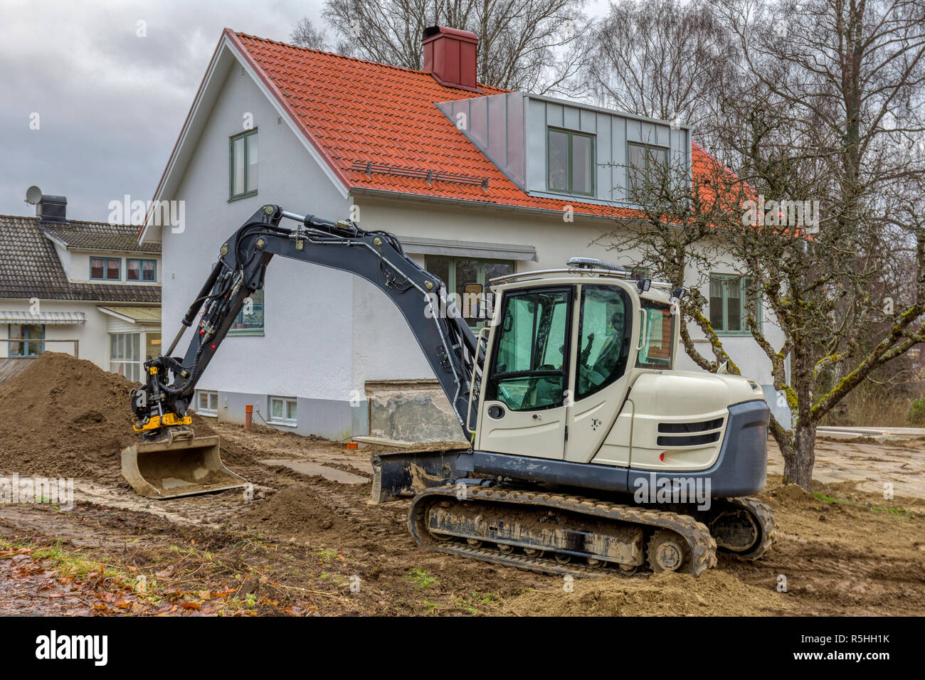 FLODA, SWEDEN - NOVEMBER 21 2018: Small excavator doing landscaping work in garden of detached house Stock Photo